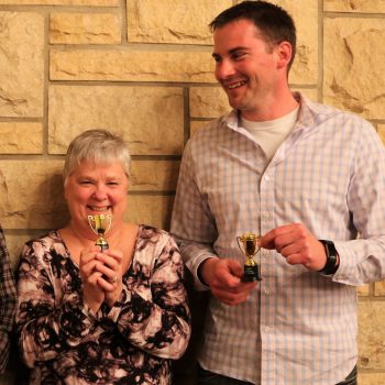Guests at murder mystery dinner party pose with trophies