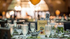 Table set for company party murder mystery dinner with salads, water, playbill, decor