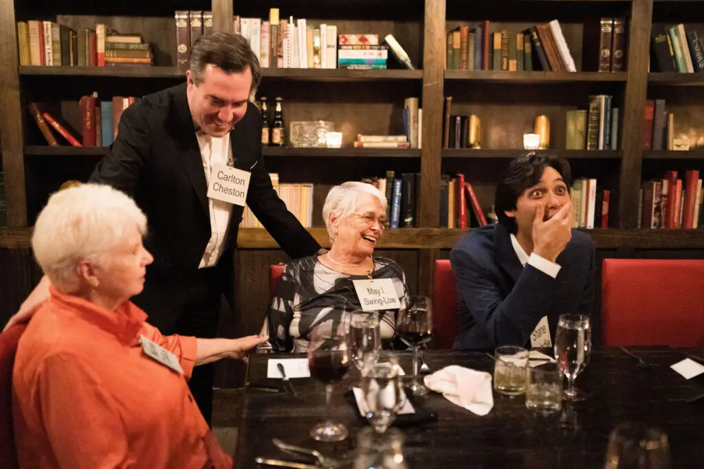 Guests laughing together during a murder mystery rehearsal dinner performance