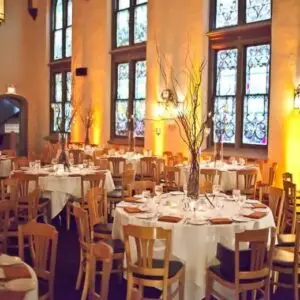 Round dining tables arranged in a dramatic historic event hall with warm lighting for a large private event