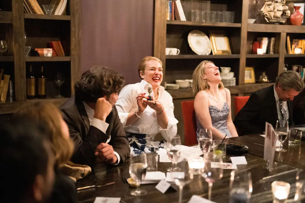 Guests sharing laughter during a private murder mystery rehearsal dinner event